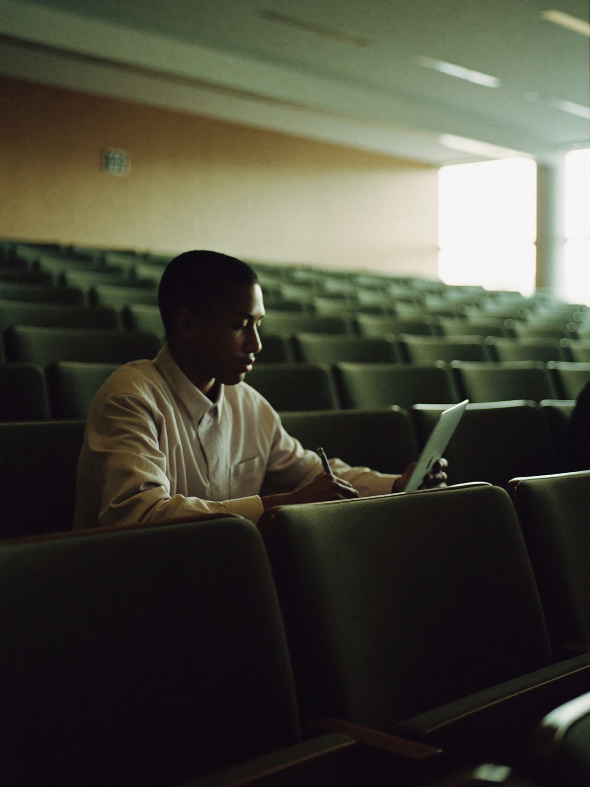A student taking notes in a lecture hall